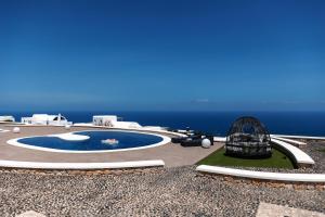 uma vista para uma piscina com o oceano ao fundo em SANTORINI GRAND LUXURY VILLAS em Imerovigli