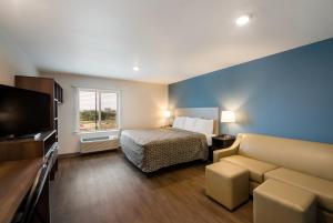 a hotel room with a bed and a couch at WoodSpring Suites Austin Central in Austin