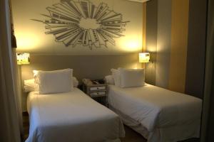 two beds in a hotel room with a clock on the wall at Sheraton São Paulo WTC Hotel in Sao Paulo