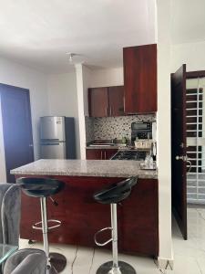 a kitchen with a counter and two bar stools at Residencial Palma Real (4to Nivel) in Santiago de los Caballeros