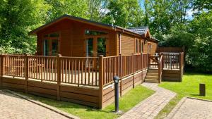 a wooden cabin with a fence and a gate at Devon Comfort Lodge with Hot Tub - Spa Resort in Devon in Chudleigh