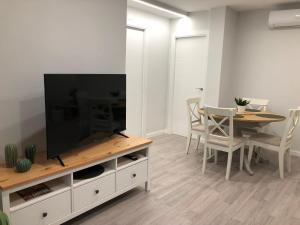 uma sala de estar com uma televisão e uma mesa com cadeiras em Apartamento Vicaño - PLAYA SILGAR em Sanxenxo