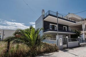 una casa bianca e nera con una palma di Luxury Beach House a Volos
