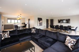 a living room with a black couch and a dining room at Mylstone House in Blackburn