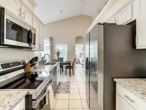 a kitchen with white cabinets and a refrigerator at Family retreat w pool near Disney & parks in Orlando