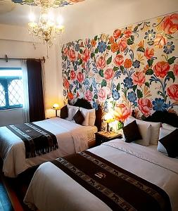 2 camas en una habitación de hotel con papel pintado floral en Casona Dorada Hotel Cusco, en Cusco