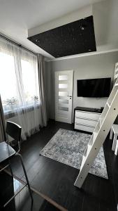 een woonkamer met een televisie en een trap erin bij Apartament Festiwalowy in Opole