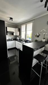 een keuken met witte kasten en een zwart aanrecht bij Apartament Festiwalowy in Opole