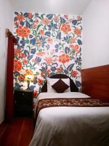 Dormitorio con cama y papel pintado con motivos florales en Casona Dorada Hotel Cusco en Cusco