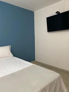 1 dormitorio con 1 cama y TV de pantalla plana en la pared en Aparta Hotel Mediterráneo Estadio en Medellín