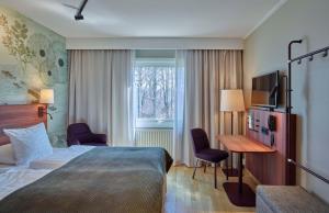 a hotel room with a bed and a desk and a window at Scandic Växjö in Växjö