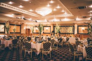 un salón de banquetes con mesas y sillas blancas en The Queen at Chester Hotel, BW Premier Collection, en Chester