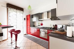 uma cozinha com armários vermelhos e bancos vermelhos em [Strategico Rho Fiera-Milano] Vanzago Home Deluxe em Vanzago