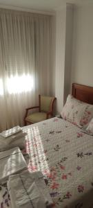 a bedroom with a bed and a chair and a window at Piso As Rodas in Villanueva de Arosa