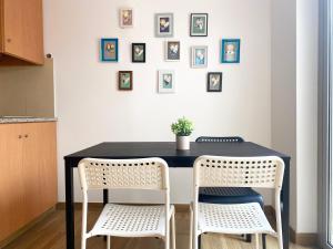 une table noire avec deux chaises et des photos sur le mur dans l'établissement Watermark Beach Apartments, à Espinho