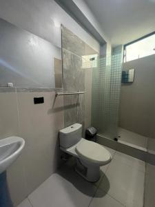 a white bathroom with a toilet and a sink at Adrian´s Hotel in Pucallpa