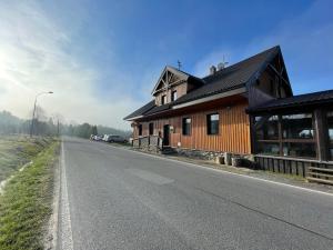 uma casa de madeira ao lado de uma estrada em Pension Korýtko em Horská Kvilda