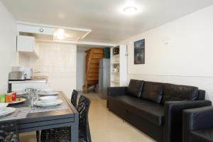 a living room with a black couch and a table at Blanc Mesnil centre ville F3 in Le Blanc-Mesnil +4 photos