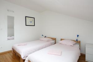 two beds in a room with white walls and wooden floors at Blanc Mesnil centre ville F3 in Le Blanc-Mesnil