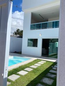 uma casa branca com uma piscina em frente em Casa Completa com piscina, 800m da praia de Jauá em Camaçari