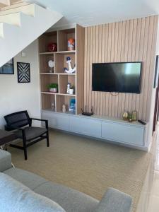 a living room with a flat screen tv on a wall at Casa Completa com piscina, 800m da praia de Jauá in Camaçari