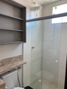a bathroom with a toilet and a glass shower at Casa Completa com piscina, 800m da praia de Jauá in Camaçari