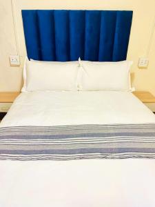 uma cama grande com uma cabeceira azul e almofadas brancas em XG Guesthouse em Barkly East