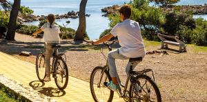 two people riding bikes on a path near the water at LUX attic old town Rab in Rab