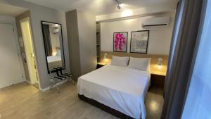 1 dormitorio con cama, escritorio y espejo en Loft Sakura - Liberdade, en São Paulo