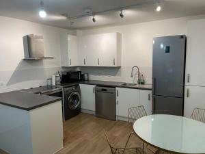 eine Küche mit einem Tisch und einem Kühlschrank in der Unterkunft Spacious 2 Bedroom Modern Flat in London