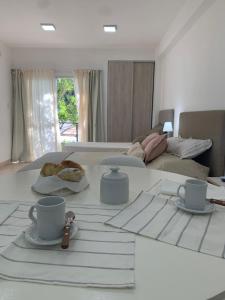 Habitación blanca con cama con mesa y tazas de café en AIKA Monoambientes en Salta