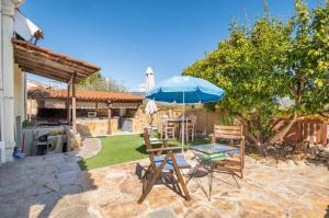 a patio with a table and an umbrella and chairs at Boem Villa in Nafpliο in Nea Kios