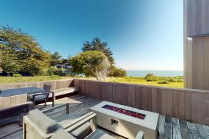 een patio met een tafel en stoelen en uitzicht op de oceaan bij Just Bluffing in Sea Ranch