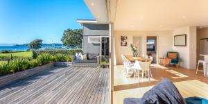 two views of a living room and dining room of a house at Onetangi Beachfront Escape - Coast & Country in Onetangi