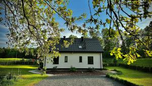 une maison blanche avec un toit noir dans l'établissement Apartamenty Karkonoska Polana, à Staniszów