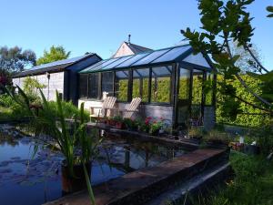 a black greenhouse with chairs and a pond at Nook in Narberth