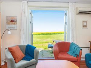 uma sala de estar com 2 cadeiras e uma porta de vidro deslizante em 6 person holiday home in Lemvig em Lemvig
