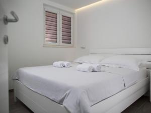 een witte slaapkamer met een wit bed en handdoeken erop bij Lavish Apartment in Imotski near Blue Lake in Imotski