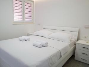 een witte slaapkamer met 2 handdoeken op een bed bij Lavish Apartment in Imotski near Blue Lake in Imotski