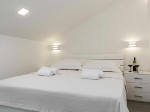 een witte slaapkamer met een groot wit bed met 2 witte kussens bij Pretty Apartment in Imotski close to River in Imotski