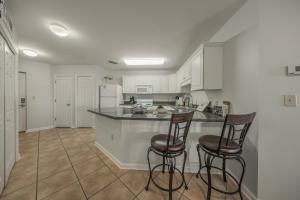 a kitchen with white cabinets and two bar stools at Grand Caribbean 312 by Vacation Homes Collection in Orange Beach
