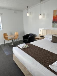 a hotel room with two beds and a table and chairs at Adelaide Airport Motel in Adelaide