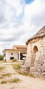 een stenen gebouw met een stenen muur ernaast bij Trullo Della Murgia - Villa in Castel del Monte