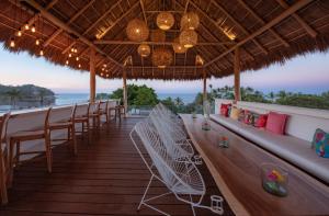 a bar with white chairs and a view of the ocean at Sayulinda Hotel in Sayulita