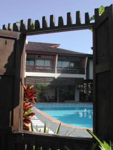 a view of a house and a swimming pool through a fence at Mae Rim Lagoon Bed & Bakery in Mae Rim