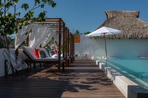 una piscina con sillas y una sombrilla junto a una piscina en Sayulinda Hotel, en Sayulita