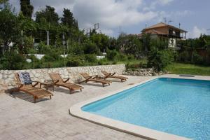 a swimming pool with chairs and a table at Elena's Summer House in Marantochori