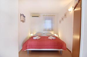 a bedroom with a red bed with two towels on it at Apartments by the sea Savudrija, Umag - 20295 in Savudrija