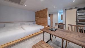 Relax Hotel Takayama Station في تاكاياما: غرفة نوم بسرير وطاولة خشبية