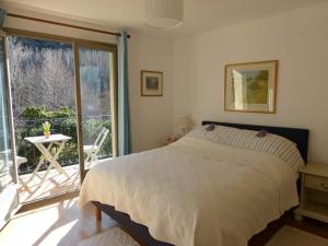 een slaapkamer met een bed en een groot raam bij villa with private swimming pool in Roquebrun